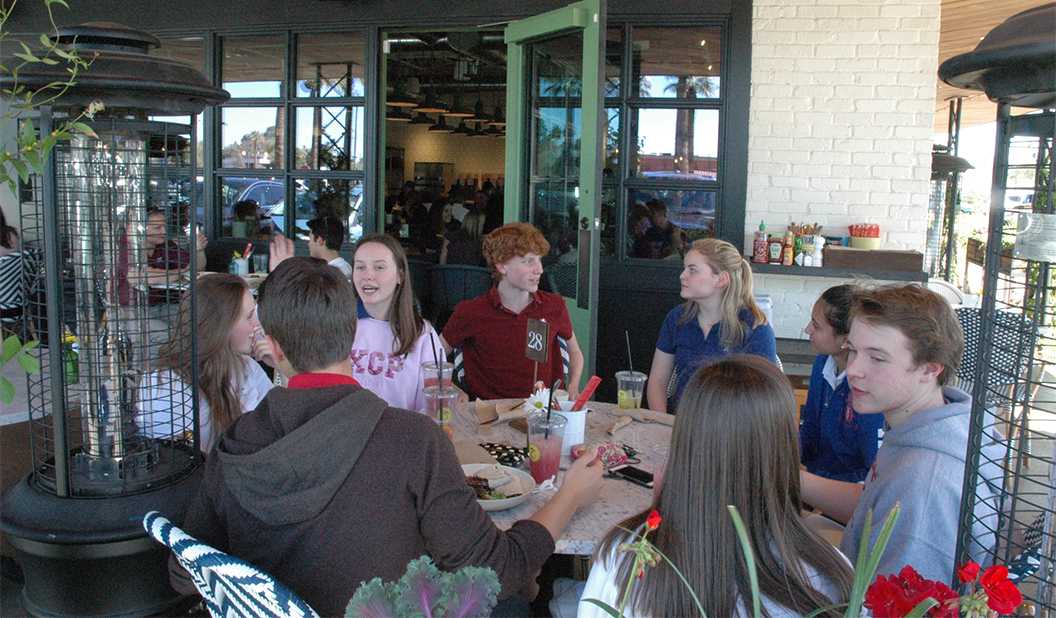Photo by Isaac Myers ’18 - Brophy and Xavier students eat outside at Flower Child. Many students eat out Friday afternoons because of the 1pm dismissal.