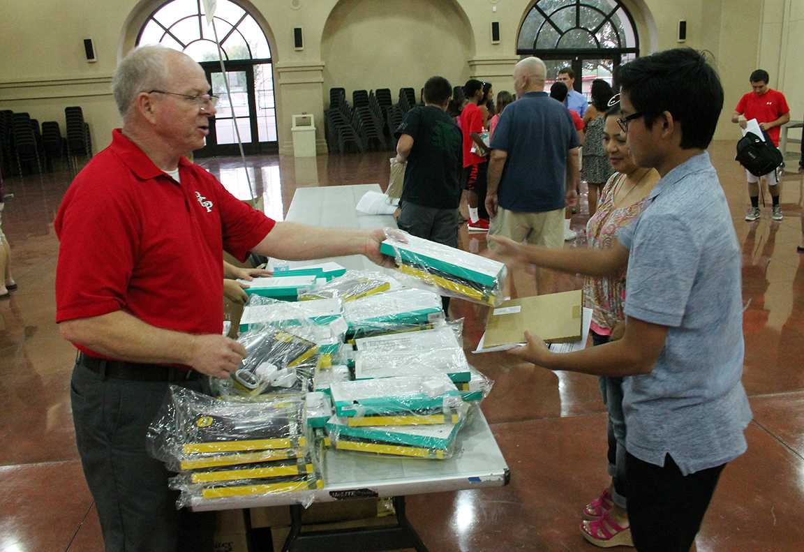 Photo by Garrison Murphy 15
Mr. Mike Elgins, left, hands equipment to an incoming freshman at the iPad rollout Aug. 4.