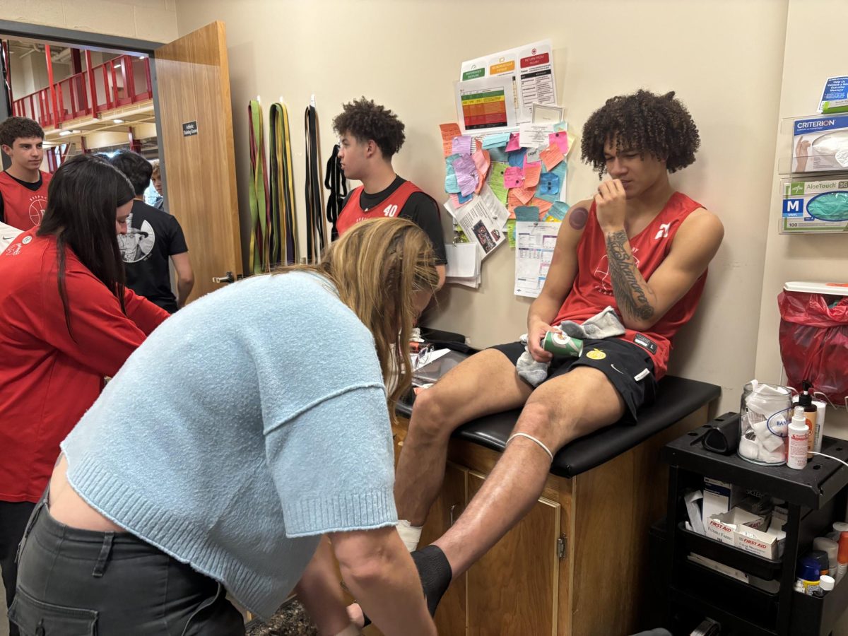 Hale Hansen ’26 gets his ankle taped by trainer Ms. Danelle Wade as part of his recovery.