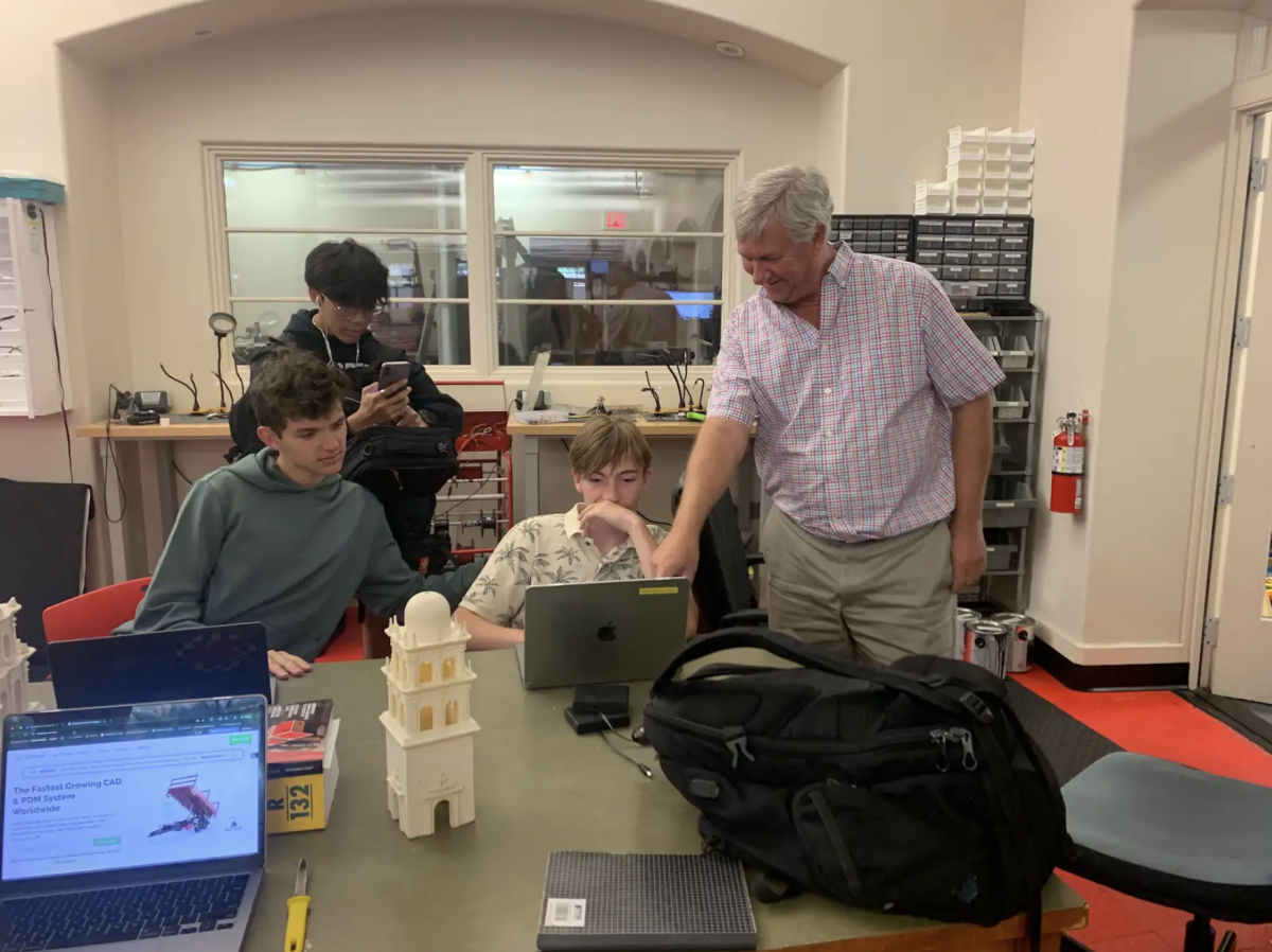 Mr. Elinsky helping a group of students sitting in the Innovation Commons. Mr. Elinski is the Head Coach of the Broncobotics team.